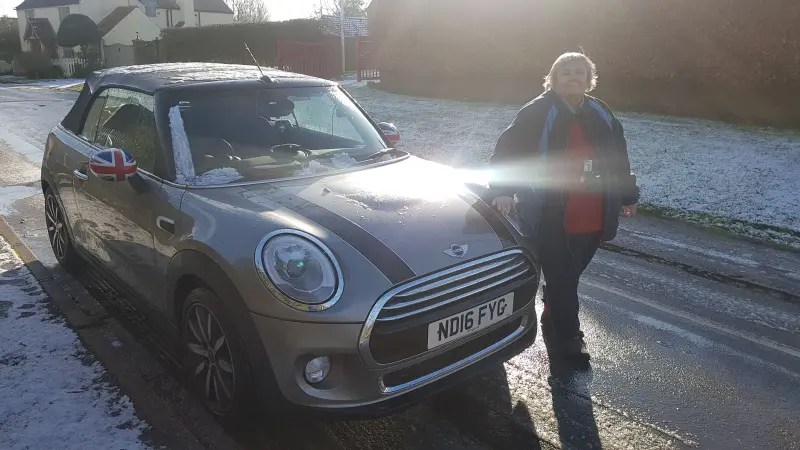 Mum standing proudly next to my Mini Cooper on a frosty morning, light shining through the trees behind her