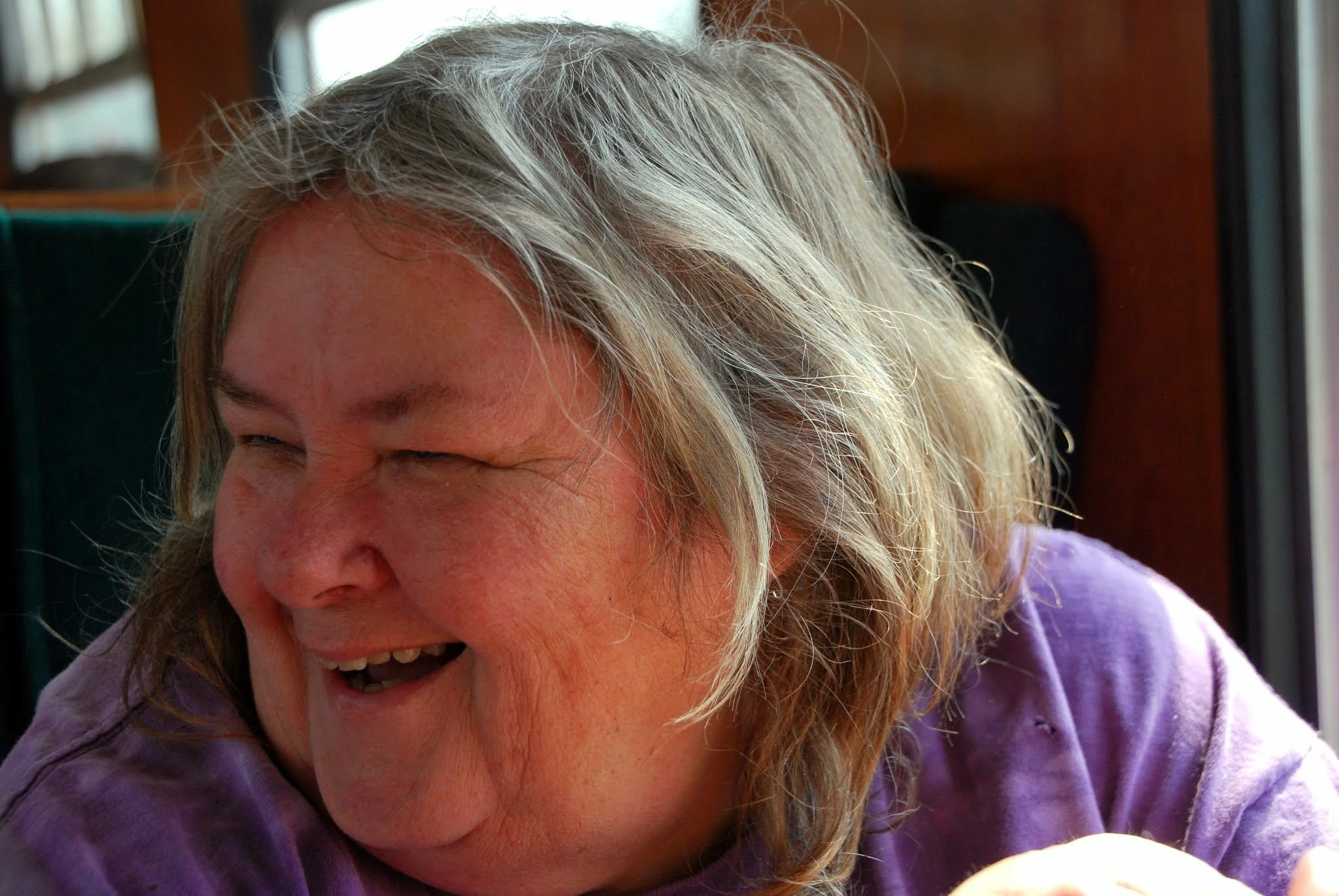 Mum laughing joyfully while wearing a purple top, her silver hair catching the light.