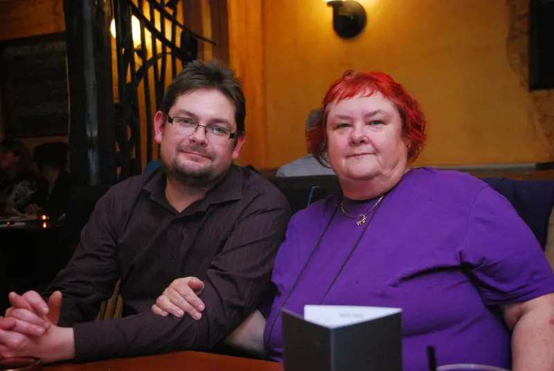 Mum with short red hair sitting beside her son at a restaurant, both looking content and close.

